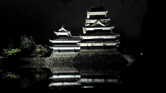 Matsumoto Castle illuminated at night reflected in the moat